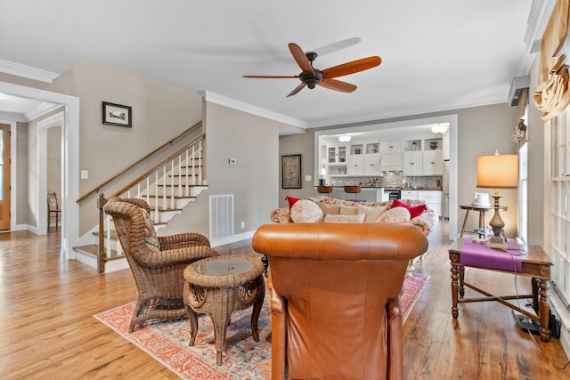 living room featuring light hardwood / wood-style floors, ceiling fan, and crown molding