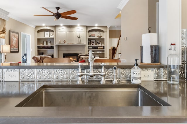 kitchen featuring ceiling fan, ornamental molding, and sink