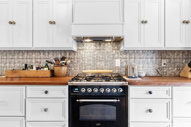 kitchen with wooden counters, tasteful backsplash, high end black range, and custom exhaust hood