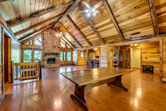 unfurnished dining area featuring light hardwood / wood-style floors, wooden ceiling, a fireplace, and wooden walls