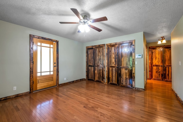 unfurnished room with ceiling fan, wood-type flooring, and a textured ceiling