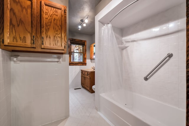 full bathroom featuring shower / bathtub combination with curtain, tile patterned flooring, toilet, vanity, and tile walls