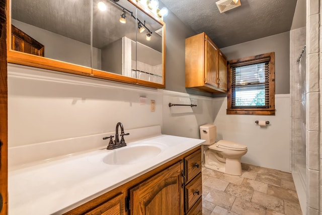 bathroom featuring vanity, a textured ceiling, and toilet