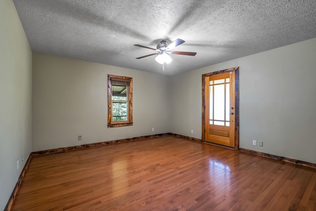 empty room with a healthy amount of sunlight, a textured ceiling, and wood-type flooring