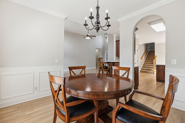 dining area with ceiling fan with notable chandelier, light hardwood / wood-style flooring, and ornamental molding