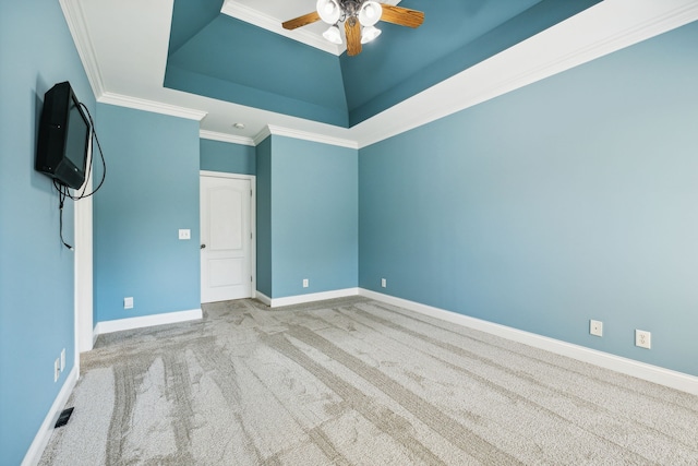 empty room featuring a tray ceiling, crown molding, ceiling fan, and light colored carpet