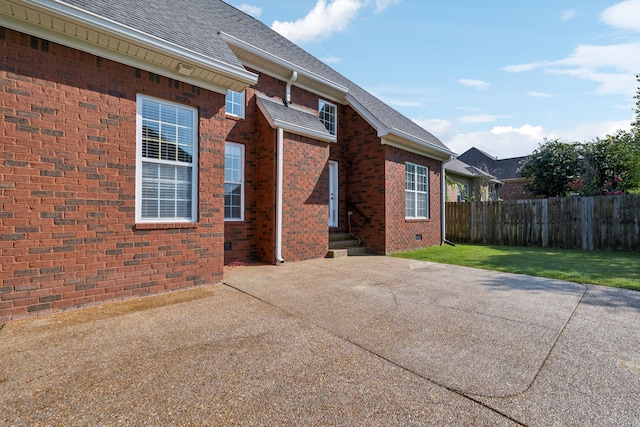 view of side of home with a patio and a lawn