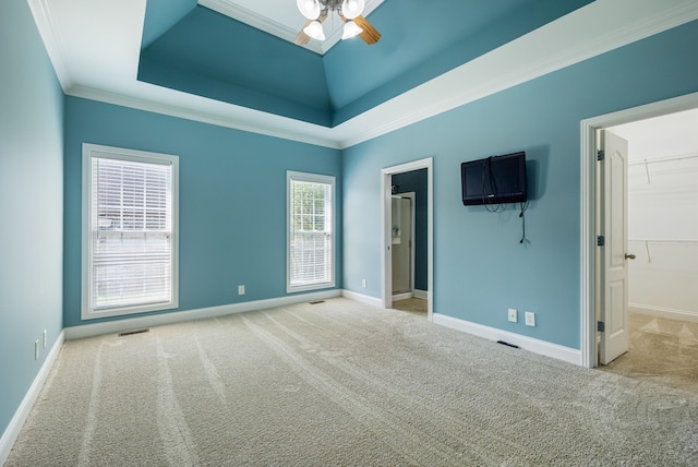 carpeted spare room featuring a raised ceiling, ceiling fan, and ornamental molding