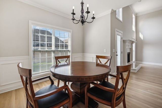 dining area featuring ornamental molding, light hardwood / wood-style flooring, and a notable chandelier