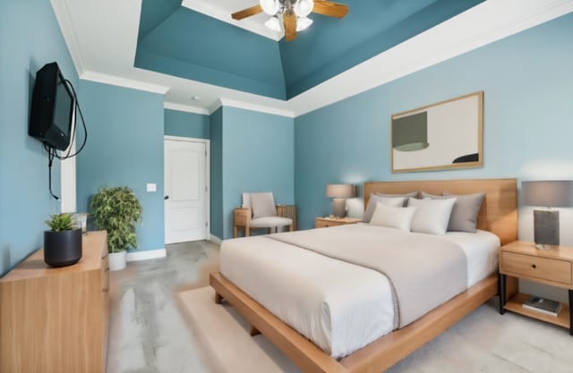 bedroom with ceiling fan, a raised ceiling, and ornamental molding