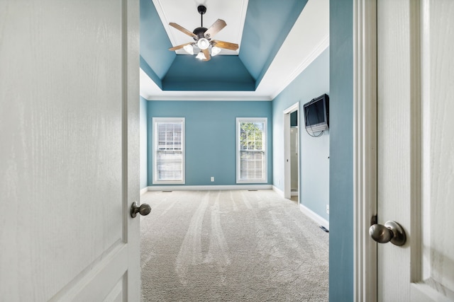 hallway with a raised ceiling, lofted ceiling, carpet floors, and ornamental molding