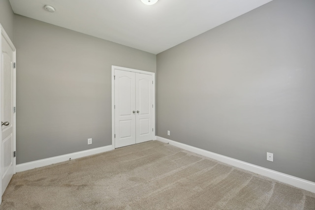 unfurnished bedroom featuring a closet and light colored carpet