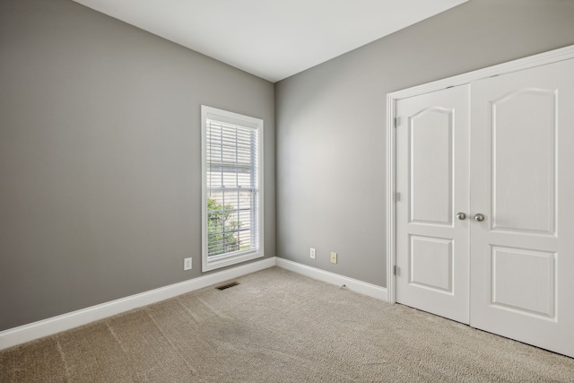 unfurnished bedroom featuring light colored carpet and a closet