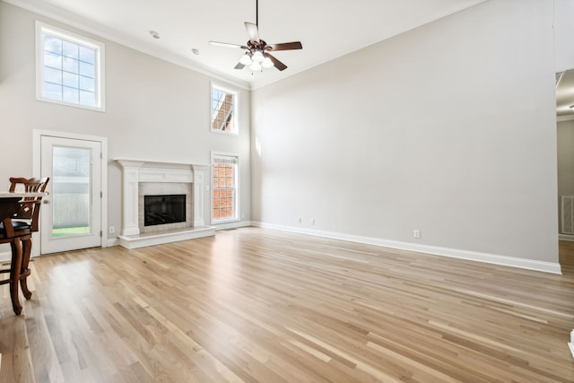 unfurnished living room with a wealth of natural light, light hardwood / wood-style floors, a high ceiling, and ornamental molding