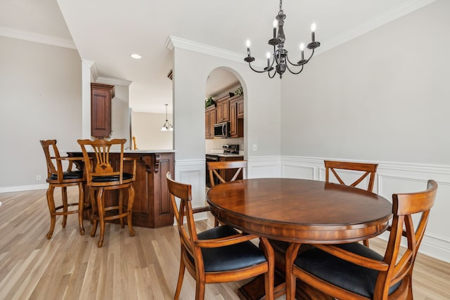 dining space featuring an inviting chandelier, ornamental molding, and light hardwood / wood-style flooring