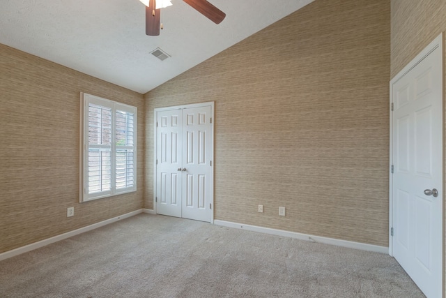 unfurnished bedroom featuring ceiling fan, a closet, high vaulted ceiling, and light carpet