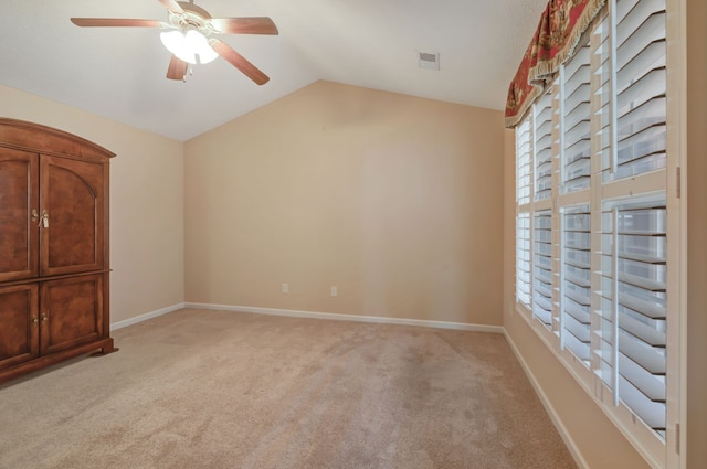 spare room featuring ceiling fan, light colored carpet, and lofted ceiling