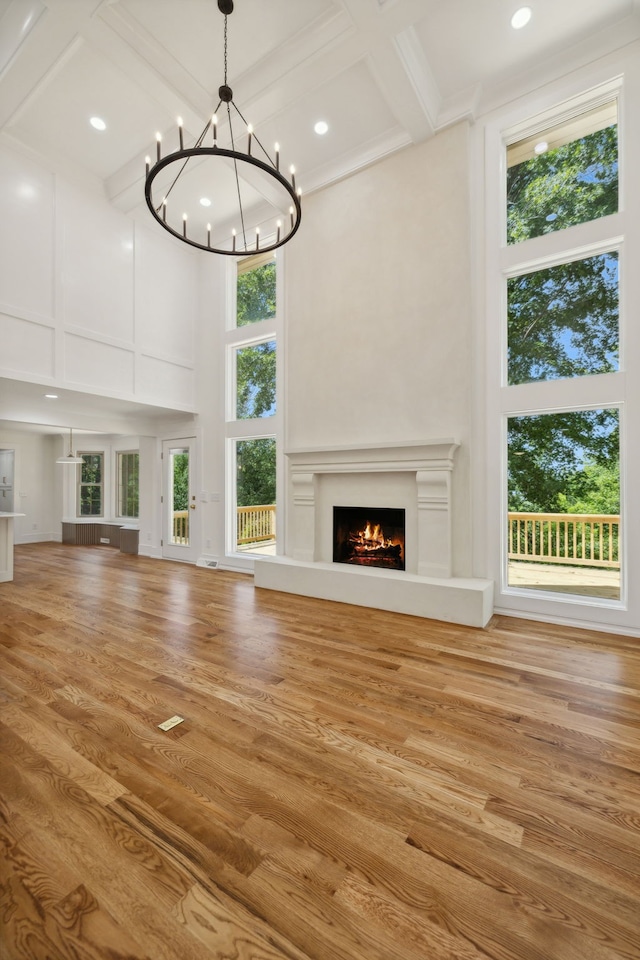 unfurnished living room featuring hardwood / wood-style floors, a towering ceiling, plenty of natural light, and beam ceiling