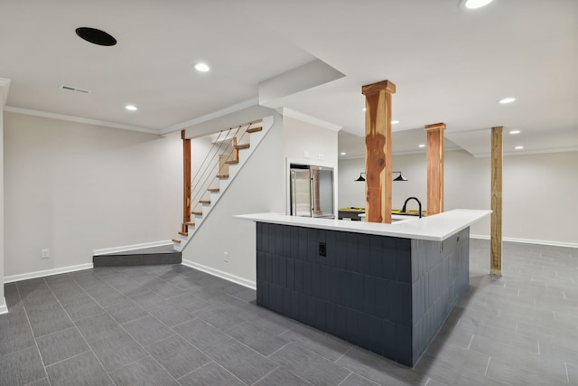 kitchen with a large island with sink, high end fridge, ornamental molding, and sink