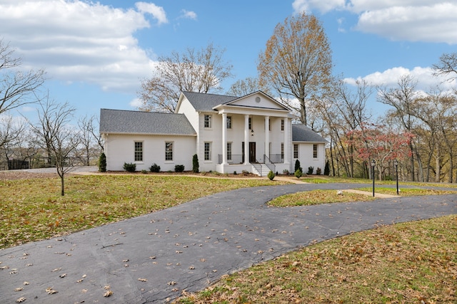 greek revival inspired property featuring a porch and a front yard