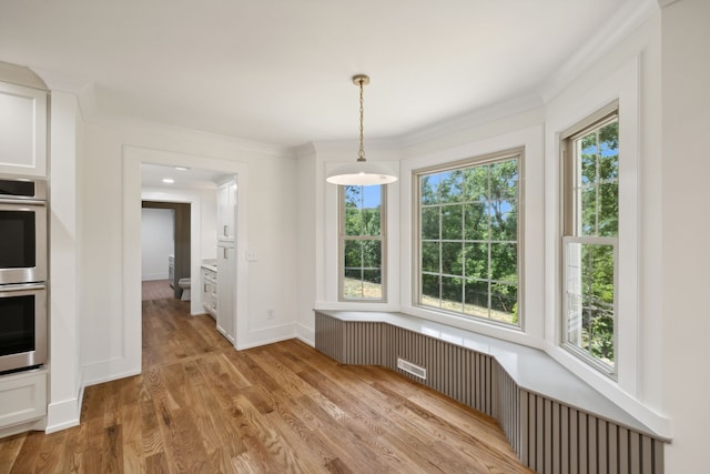 unfurnished dining area with crown molding, plenty of natural light, and light wood-type flooring