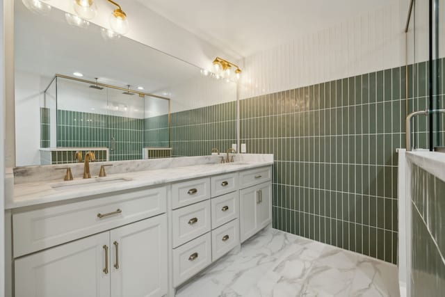 bathroom with vanity, a shower with door, and tile walls