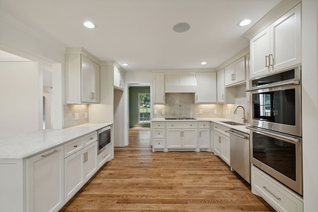 kitchen featuring sink, light hardwood / wood-style flooring, white cabinetry, custom range hood, and stainless steel appliances