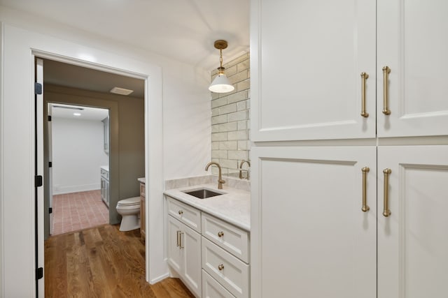 bathroom featuring hardwood / wood-style floors, vanity, toilet, and decorative backsplash