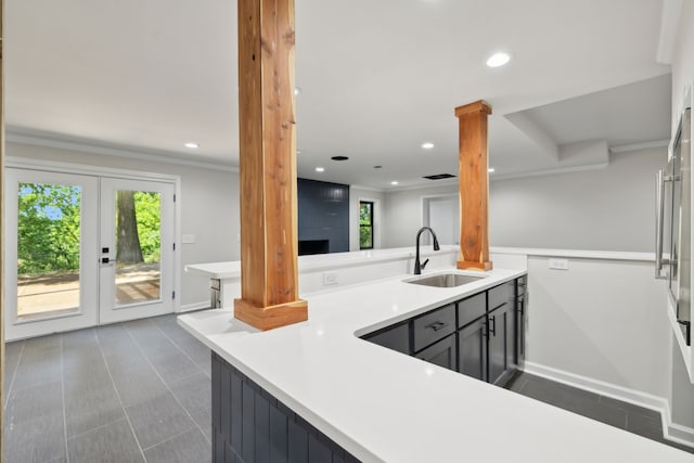 kitchen with french doors, sink, ornamental molding, kitchen peninsula, and decorative columns