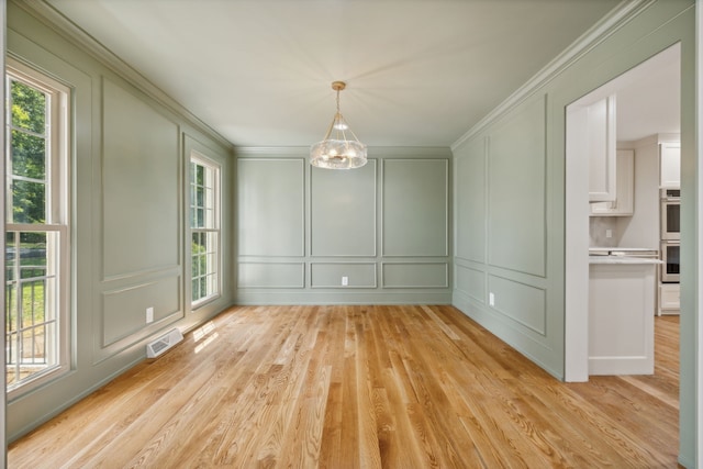 unfurnished dining area featuring a notable chandelier, light hardwood / wood-style floors, and ornamental molding