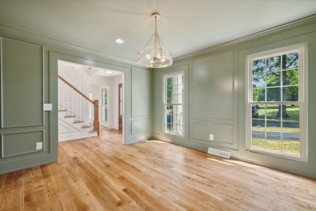 unfurnished dining area featuring crown molding, light hardwood / wood-style flooring, and a notable chandelier