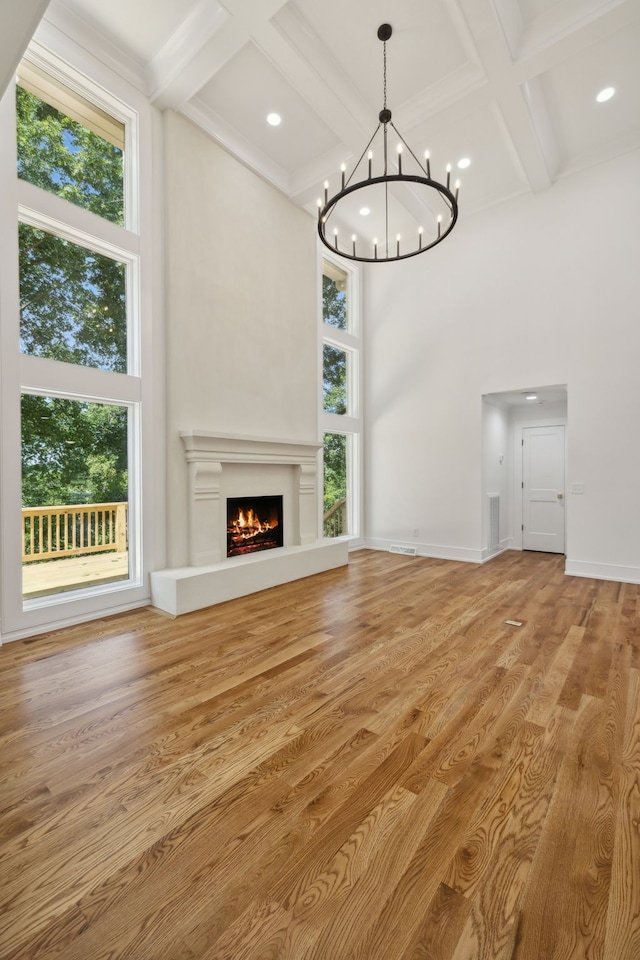 unfurnished living room with a healthy amount of sunlight, a towering ceiling, and wood-type flooring