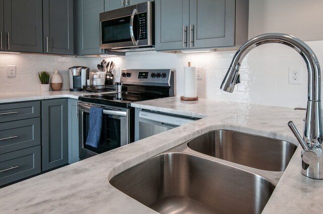 kitchen with light stone countertops, backsplash, and appliances with stainless steel finishes