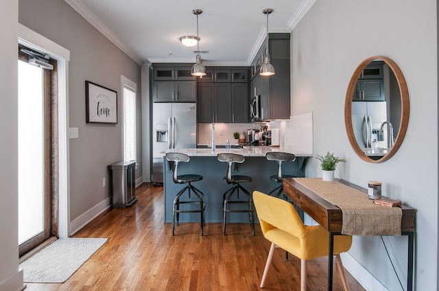 kitchen featuring kitchen peninsula, stainless steel appliances, dark wood-type flooring, and ornamental molding