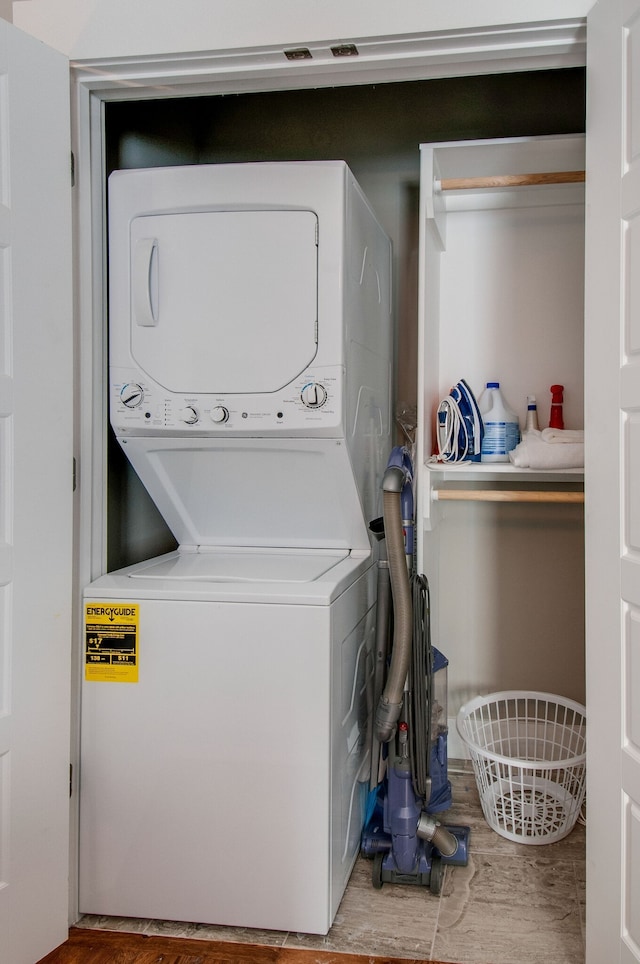 laundry room with hardwood / wood-style floors and stacked washing maching and dryer