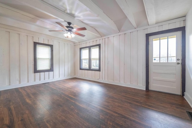 unfurnished room featuring a healthy amount of sunlight, lofted ceiling with beams, ceiling fan, and dark wood-type flooring