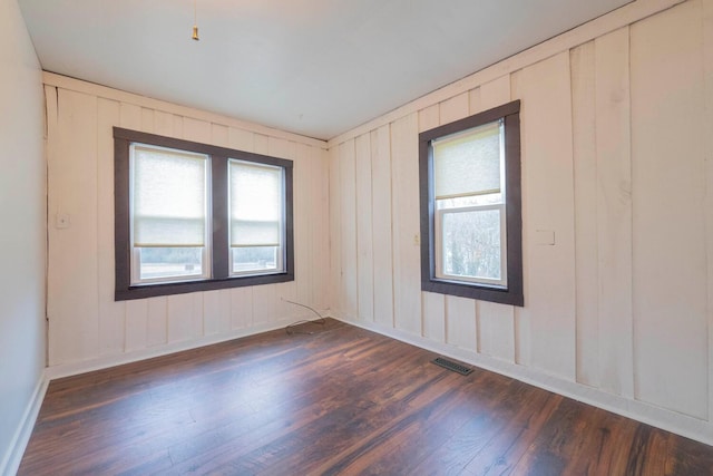 unfurnished room with plenty of natural light and dark wood-type flooring