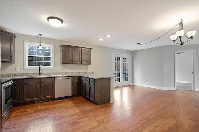 kitchen with sink, stainless steel appliances, decorative light fixtures, and hardwood / wood-style flooring