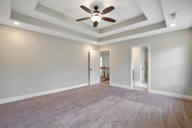 unfurnished bedroom featuring carpet flooring, a raised ceiling, and ceiling fan