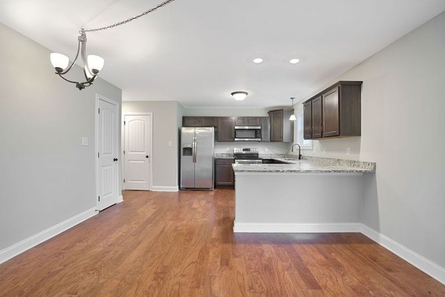 kitchen featuring light stone countertops, appliances with stainless steel finishes, dark hardwood / wood-style floors, and pendant lighting