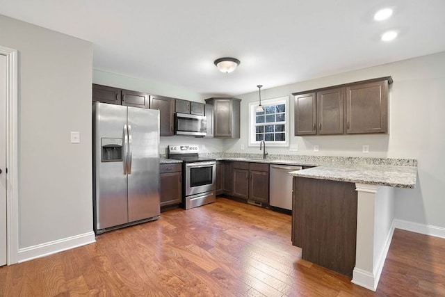 kitchen featuring pendant lighting, sink, dark hardwood / wood-style floors, appliances with stainless steel finishes, and kitchen peninsula