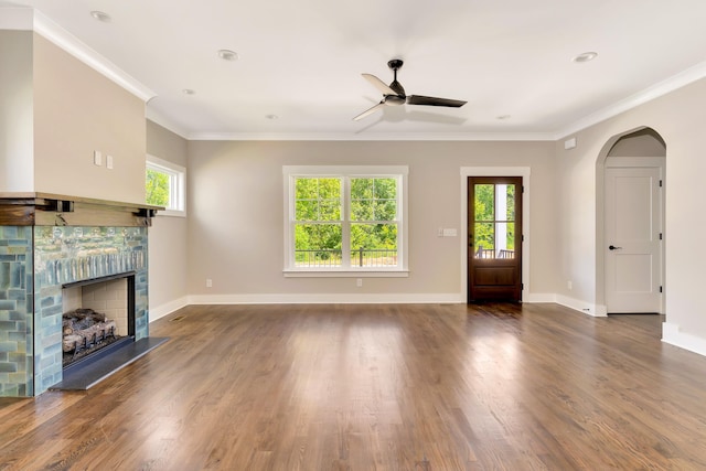 unfurnished living room featuring a fireplace with raised hearth, crown molding, and wood finished floors