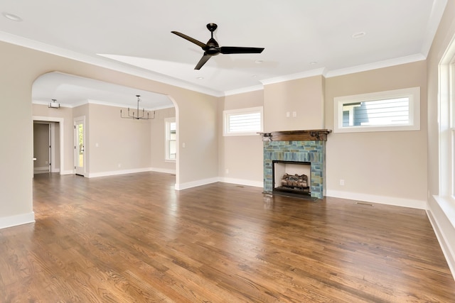 unfurnished living room with crown molding, a fireplace, ceiling fan with notable chandelier, and hardwood / wood-style flooring