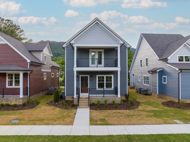 view of front of house featuring a porch, a front yard, a balcony, and central air condition unit