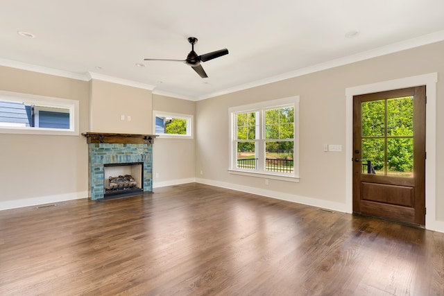 unfurnished living room featuring dark wood-style floors, a stone fireplace, baseboards, and crown molding