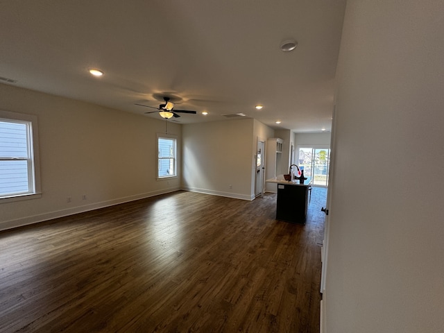 unfurnished living room with ceiling fan, a healthy amount of sunlight, and dark hardwood / wood-style flooring