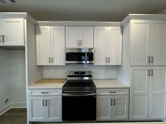 kitchen featuring white cabinetry, light stone countertops, tasteful backsplash, and stainless steel appliances