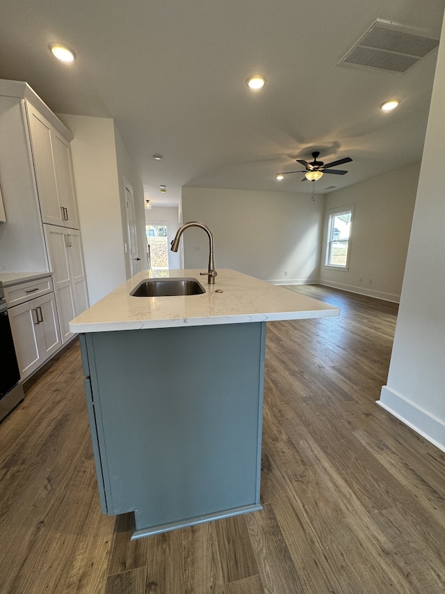 kitchen featuring white cabinetry, sink, dark wood-type flooring, and an island with sink