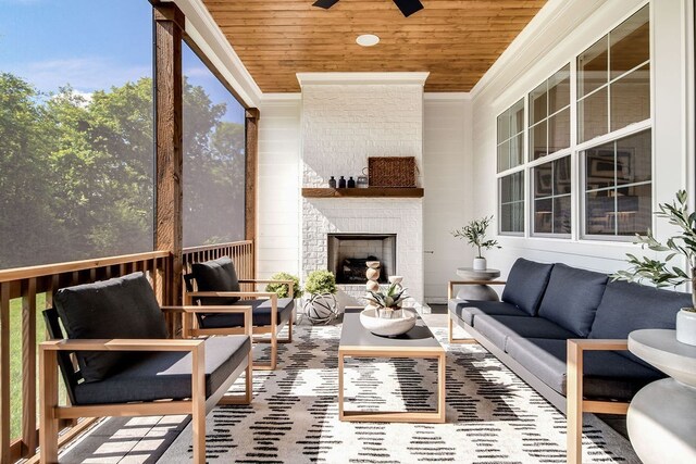 sunroom with wooden ceiling, a brick fireplace, and a ceiling fan