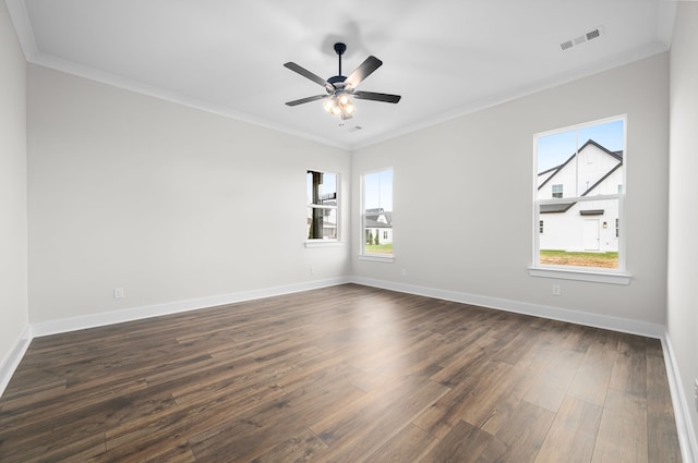 empty room featuring dark wood finished floors, visible vents, crown molding, and baseboards